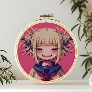 May include: A cross-stitch embroidery hoop with a pink background and a cartoon image of a girl with blonde hair and green eyes. The girl is wearing a blue and white sailor uniform and has a large smile.