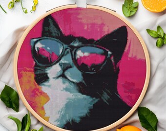 May include: A black and white cat wearing sunglasses with a pink and yellow background. The cat is looking to the right. The image is in a round wooden frame.