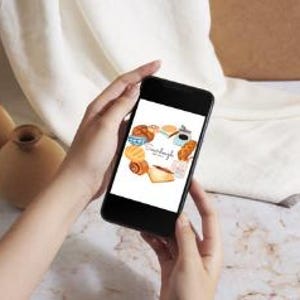 May include: A smartphone displaying a graphic of a heart shape made of various baked goods, including croissants, bread, and coffee. The text "Sunday Morning" is inside the heart.