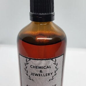 May include: A brown glass bottle with a black dropper top. The bottle is labelled "Chemical & Jewellery Silver Test Solution 100ml".