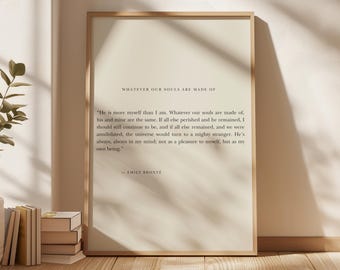 Op de afbeelding: Een ingelijste print met de quote "WHATEVER OUR SOULS ARE MADE OF" en een passage van Emily Brontë. De print heeft een lichtbeige achtergrond en een houten lijst. Boeken en een plant zijn zichtbaar op de voorgrond.