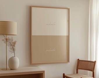 May include: A framed wall art piece with a two-tone design. The top half is off-white, the bottom half is tan. The words "inhale" and "exhale" are written in cursive. The frame is made of light wood.