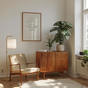 May include: A mid-century modern living room with a wooden cabinet, a beige armchair, a floor lamp, and a framed print with the text "Write it in your heart".