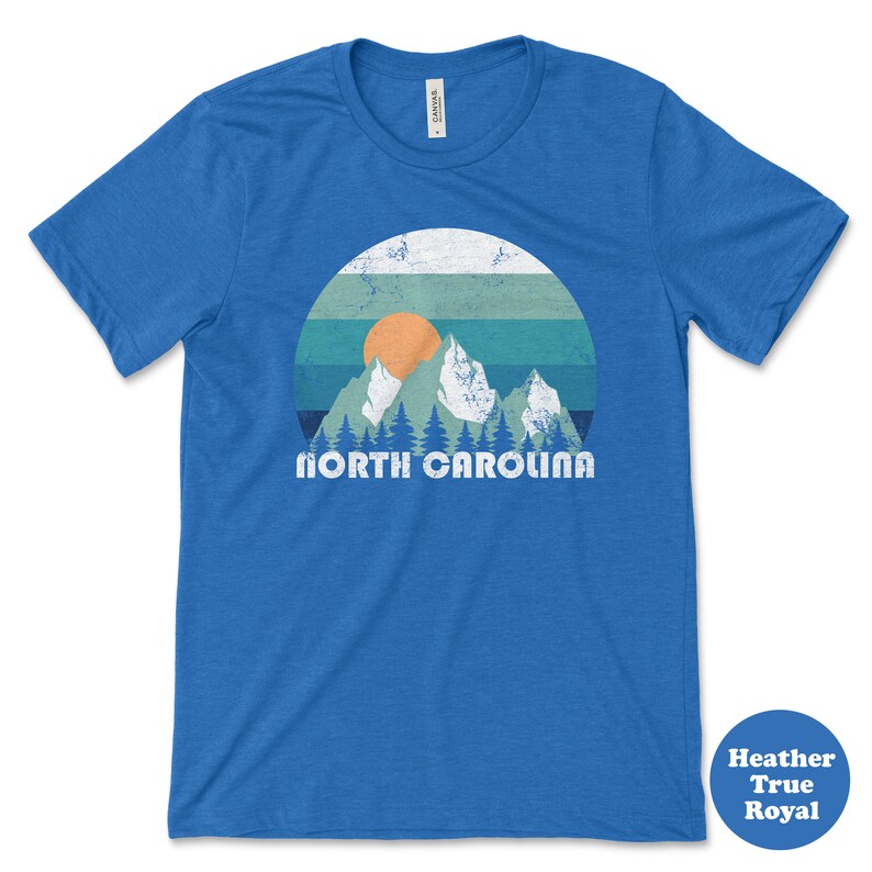 May include: A blue t-shirt with a vintage-style graphic of mountains and a sunset with the text "NORTH CAROLINA" in white.