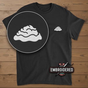 May include: Black t-shirt with a white embroidered cloud design on the chest. A larger, detailed view of the cloud is shown in a circular inset. The word "EMBROIDERED" is displayed below the shirt.
