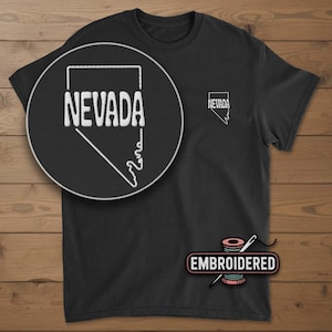 May include: Black t-shirt with a white embroidered outline of the state of Nevada. The word "NEVADA" is embroidered in white within the state outline. A smaller Nevada outline is on the chest. The word "EMBROIDERED" is below the shirt.
