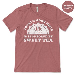 May include: Heather mauve t-shirt with a white graphic of a smiling sun with the text "Today's Good Mood Is Sponsored By Sweet Tea".