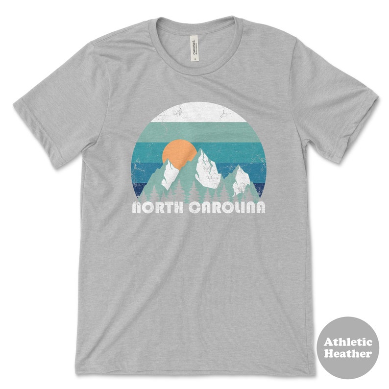 May include: A gray t-shirt with a vintage-style graphic of mountains, a sunset, and the text "NORTH CAROLINA".