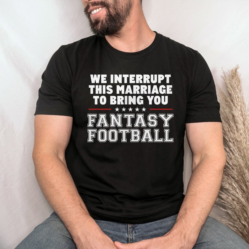 May include: A black t-shirt with white text that reads "We interrupt this marriage to bring you Fantasy Football".
