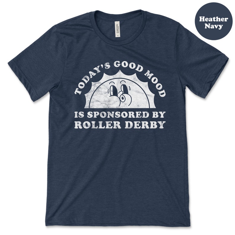 Op de afbeelding: Een hemelsblauw t-shirt met een witte afbeelding van een lachende zon met de tekst "Today's Good Mood Is Sponsored By Roller Derby".
