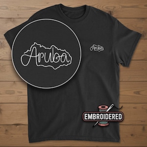May include: Black t-shirt with white embroidered outline of Aruba and the word "Aruba". A close-up shows the embroidered design. The word "Embroidered" is displayed below the shirt with a needle and thread.