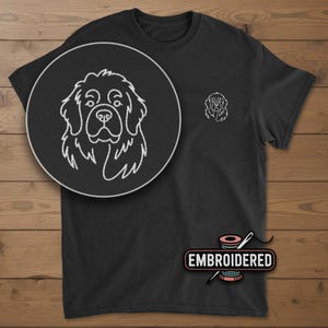 May include: Black t-shirt with a white embroidered outline of a Newfoundland dog's face on the chest and a smaller version on the left breast. The word "EMBROIDERED" is displayed in a pink and white design.