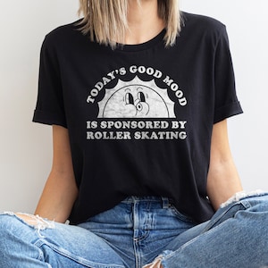 May include: A black t-shirt with a white graphic of a smiling sun with the text "Today's Good Mood Is Sponsored By Roller Skating".