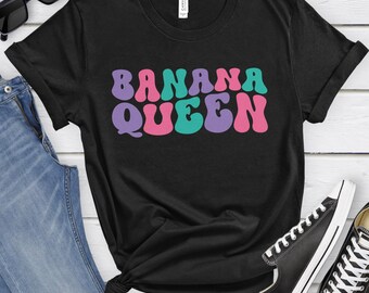 May include: Black t-shirt with the text "BANANA QUEEN" in pink, purple, and teal retro lettering.
