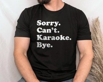 May include: A black t-shirt with white text that reads "Sorry. Can't. Karaoke. Bye."