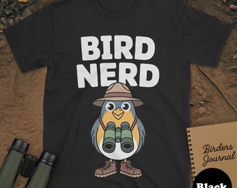May include: Black t-shirt featuring the text "BIRD NERD" in white. A cartoon bird with a hat and binoculars is below the text. A notebook with "Birders Journal" is on the right, with a black circle below it.