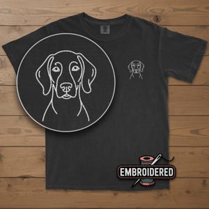 May include: Dark gray t-shirt featuring a white embroidered outline of a dog's face on the chest and a larger, detailed version in a circular inset. The word "EMBROIDERED" is displayed on a label below the shirt.