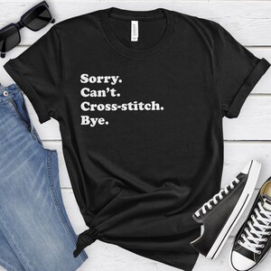 May include: Black t-shirt with white text that reads "Sorry. Can't. Cross-stitch. Bye."