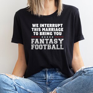 May include: A black t-shirt with white text that reads "We interrupt this marriage to bring you Fantasy Football".