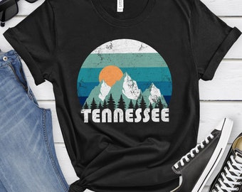 May include: Black t-shirt with a vintage-style graphic of mountains, a sun, and the word "Tennessee".
