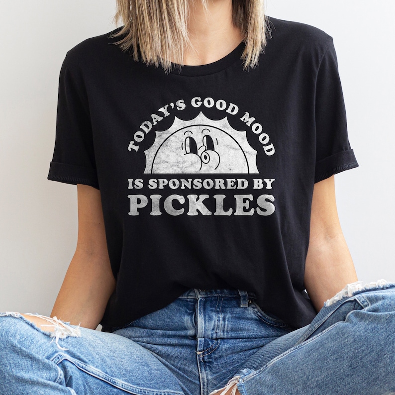 May include: Black t-shirt with a white graphic of a smiling sun with the text "Today's Good Mood Is Sponsored By Pickles".