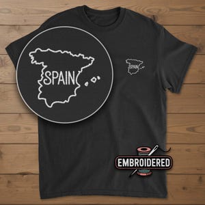 May include: Black t-shirt with an embroidered outline of Spain and the word "SPAIN" in white. A larger, detailed embroidered image of Spain is shown in a circular inset. The word "EMBROIDERED" is printed below the shirt.