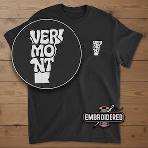 May include: Black t-shirt with a white embroidered design of the state of Vermont and the word "VERMONT". A smaller version of the design is on the upper chest. The word "EMBROIDERED" is below the shirt.