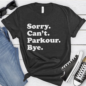May include: A dark grey t-shirt with white text that reads "Sorry. Can't. Parkour. Bye."