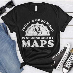 May include: Black t-shirt with a white graphic of a smiling sun with the text "Today's Good Mood Is Sponsored By MAPS".