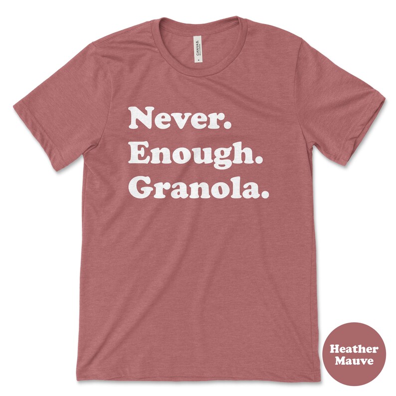 May include: A heather mauve t-shirt with the text "Never. Enough. Granola." printed in white.