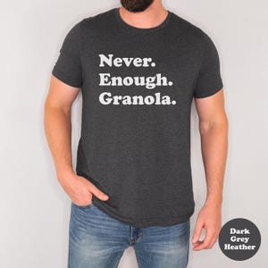 May include: A dark grey heather t-shirt with the text "Never. Enough. Granola." printed in white.