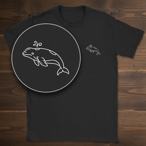 May include: A black short-sleeved t-shirt featuring a small, white, minimalist line-art graphic of a beluga whale on the left chest. The whale is depicted in profile with a small water spout emerging from its head and a circular spot on its back.