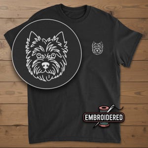 May include: Black t-shirt with a white embroidered dog face on the chest and a larger, detailed version in a circular inset. The word "EMBROIDERED" is displayed below the shirt in a pink and white design.