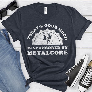 May include: A navy blue t-shirt with a white graphic of a smiling sun with the text "Today's Good Mood Is Sponsored By Metalcore".