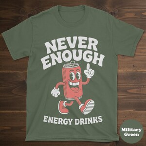 May include: Military green t-shirt with the text "NEVER ENOUGH ENERGY DRINKS" in white. The design features a cartoon energy drink can with a smiling face, arms, and legs, pointing upwards.