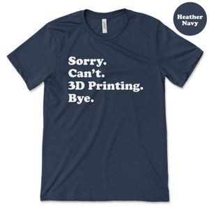 Pu&ograve; includere: T-shirt blu navy melange con la scritta bianca "Sorry. Can't. 3D Printing. Bye." La maglietta ha girocollo e maniche corte. Un cerchio blu navy in alto a destra indica "Heather Navy."