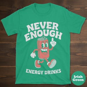 May include: Irish green t-shirt with the words "NEVER ENOUGH ENERGY DRINKS" in white. A cartoon soda can character with a smiling face and red color is featured in the center, pointing upwards.