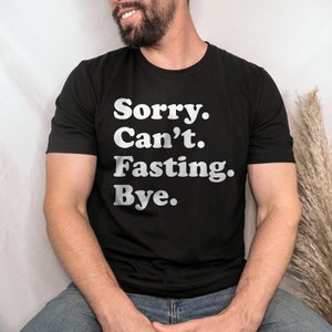 May include: A black t-shirt with the text "Sorry. Can't. Fasting. Bye." printed in white.