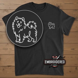 May include: Black t-shirt with a white embroidered outline of a dog on the chest and a larger, detailed version in a circular inset. The word "EMBROIDERED" is displayed below the shirt, along with a needle and thread.