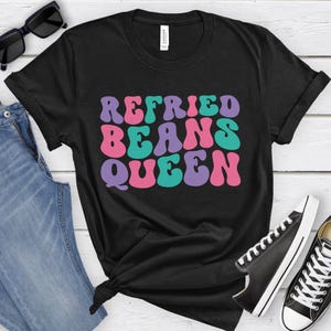 May include: Black t-shirt with the text "Refried Beans Queen" in colorful retro font.