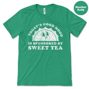 May include: Green t-shirt with a white distressed graphic that says "Today's Good Mood Is Sponsored By Sweet Tea" with a cartoon sun face.