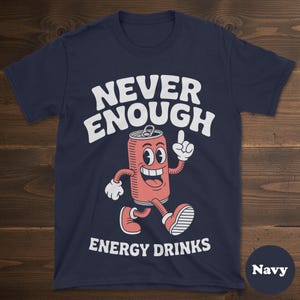 May include: Navy blue t-shirt with the words "NEVER ENOUGH ENERGY DRINKS" in white. The shirt features a cartoon image of a smiling energy drink can with arms and legs, pointing upwards.