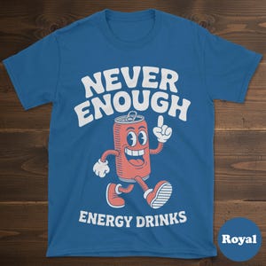 May include: Royal blue t-shirt with the words "NEVER ENOUGH ENERGY DRINKS" in white. A cartoon image of a smiling red soda can with white gloves and shoes is in the center. The shirt is made of a soft material.