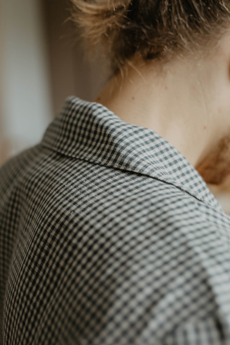 May include: Close-up of a black and white gingham shirt collar. The fabric is soft and textured.