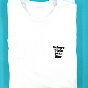 Könnte beinhalten: Weißes T-Shirt mit schwarzem Text, der "Schere Stein Paar Bier" lautet