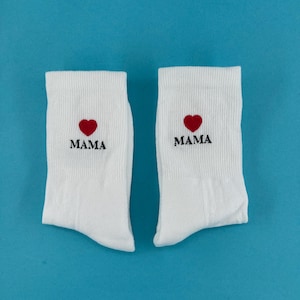 Könnte beinhalten: Ein Paar weiße Socken mit einem roten Herzen und dem Wort "MAMA" auf jeder Socke gestickt.