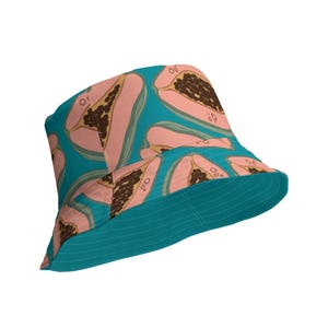 Può includere: Un cappello a secchiello blu turchese con una stampa di papaia rosa e marrone. Il cappello ha un'ampia tesa e una corona piatta.