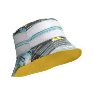 Può includere: Un cappello a secchiello con motivo blu e bianco con il lato inferiore giallo. Il cappello ha un'ampia tesa ed è realizzato in un tessuto morbido e leggero.