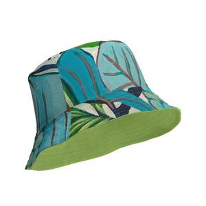 Può includere: Un cappello a secchiello verde e blu con un motivo a foglie tropicali. Il cappello ha un lato inferiore verde.