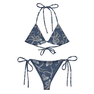 Puede incluir: Un bikini azul con estampado de pulpo. La parte superior es de estilo triangular con tirantes ajustables y lazos en la espalda. La parte inferior es de estilo atrevido con lazos a los lados.